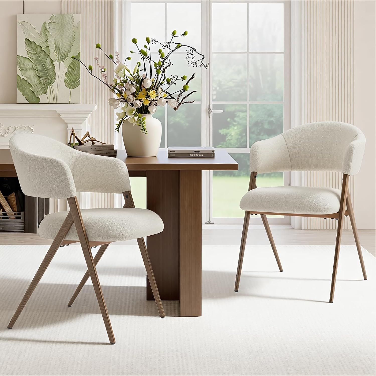 Pair of cream boucle accent chairs with wood-toned iron legs in a sunlit dining nook