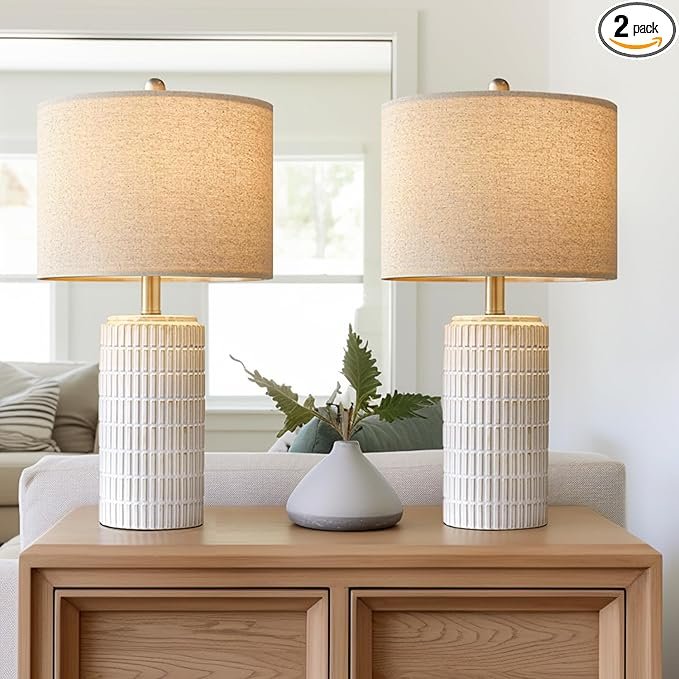 Pair of textured cream ceramic table lamps with oat linen shades on a warm wood console